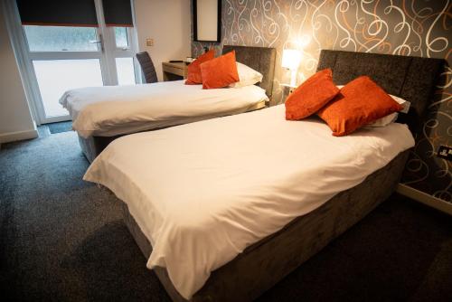 2 camas con almohadas de color naranja en una habitación de hotel en The Dwelling Place, en Irvine