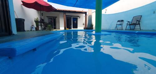 a blue swimming pool with an umbrella and chairs at Casa Kanté in Tamasopo
