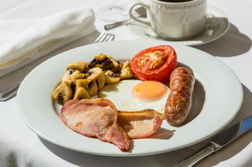 a plate of breakfast food with eggs bacon sausage and waffles at The Lordleaze Hotel And Restaurant in Chard