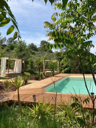 une piscine dans un jardin avec une terrasse en bois dans l'établissement Nuitées Bohèmes, à Gajan