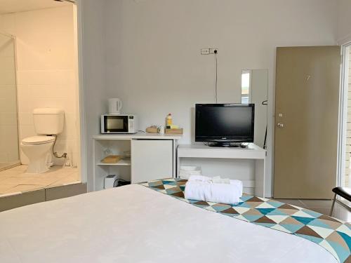 a room with a bed and a tv and a bathroom at Aqua Blue Motel in Gold Coast