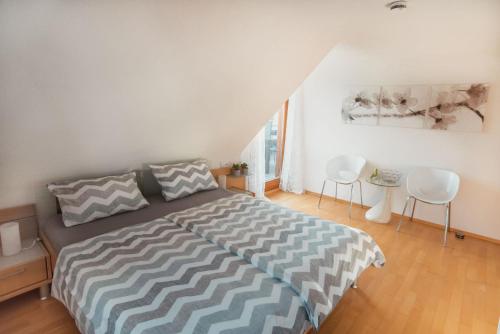 a bedroom with a bed and two white chairs at OBSTHAUS Ferienwohnung Apfel in Sipplingen