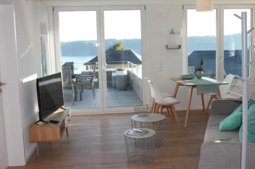 a living room with a couch and a tv and a balcony at REBHAUS Ferienwohnung Rebdach in Sipplingen
