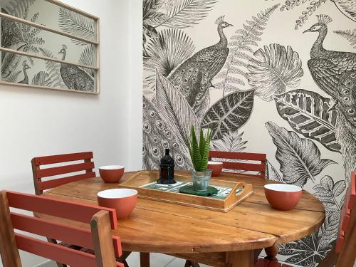 a dining room with a wooden table and a wallpaper with peacocks at LA MAISON DU PORT in Plérin