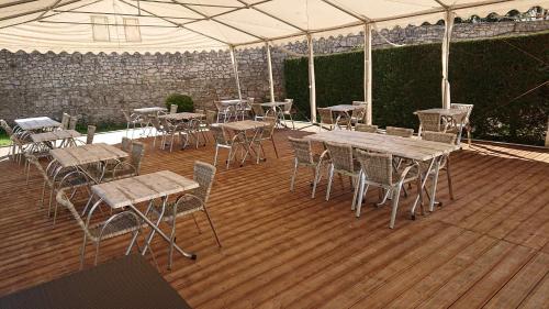 a wooden deck with tables and chairs under a tent at Auberge le Cévenol in La Cavalerie