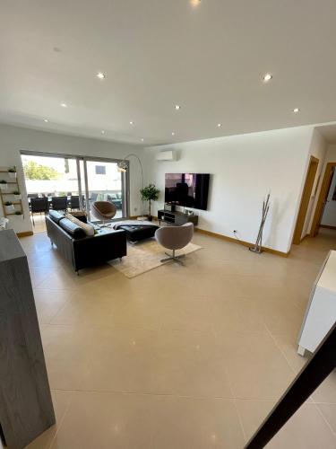 a living room with a black couch and a tv at Beach condo Porto mós (sea view) in Lagos