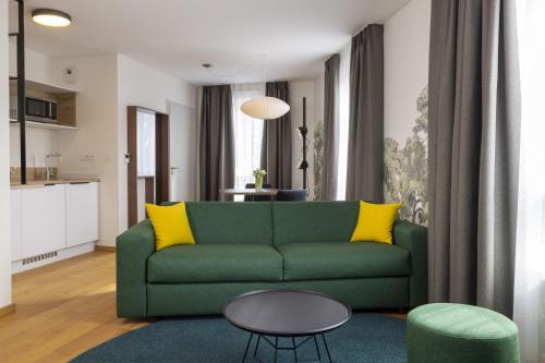 a living room with a green couch and yellow pillows at Hôtel Du Dragon in Strasbourg