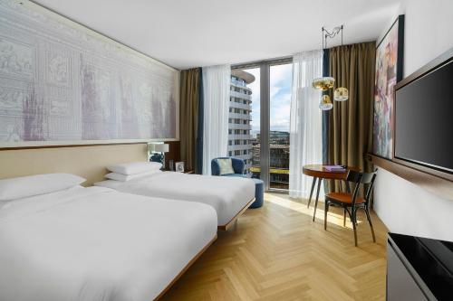 a hotel room with two beds and a flat screen tv at Andaz Vienna Am Belvedere - a concept by Hyatt in Vienna