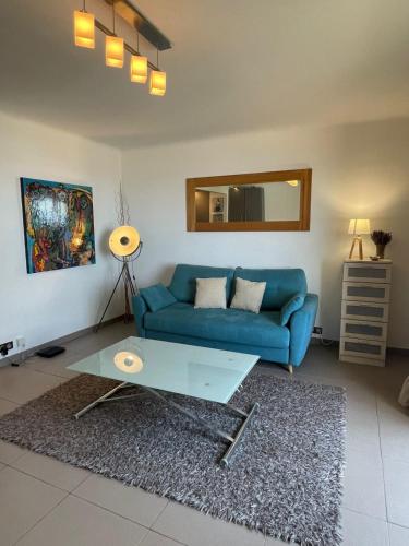 un salon avec un canapé bleu et une table dans l'établissement Fully equipped beachfront studio in the heart of the city center bd Leclerc, à Antibes