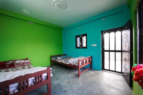 a room with two beds and green walls at Village Homestay with Culture and Nature in Pokhara