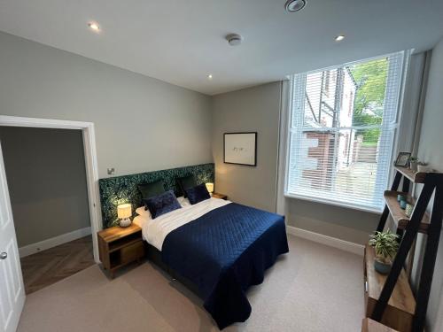 a bedroom with a bed with blue sheets and a window at Crown and Cushion Appleby in Appleby