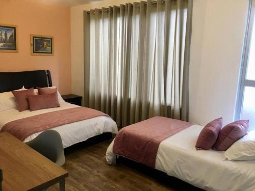 a hotel room with two beds and a window at CASA VACACIONAL CAPINA87 in Pereira
