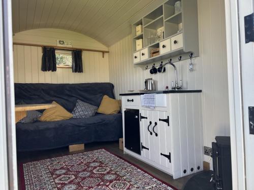 uma pequena sala de estar com um sofá e um fogão em Home Farm Shepherds Hut with Firepit and Wood Burning Stove em High Wycombe