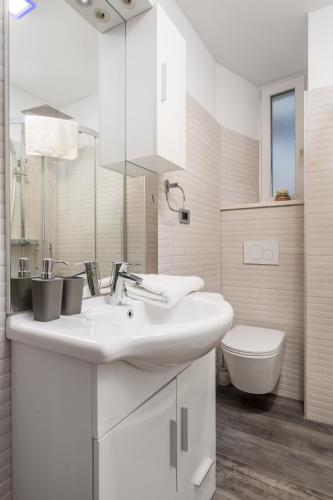 a white bathroom with a sink and a toilet at Rijeka Old Town Apartment in Rijeka