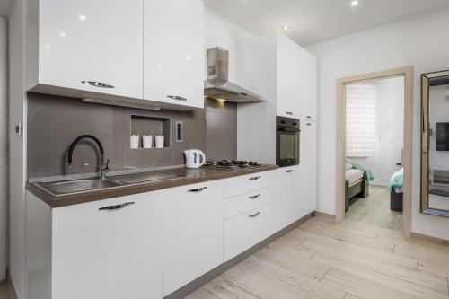 a kitchen with white cabinets and a sink at Rijeka Old Town Apartment in Rijeka