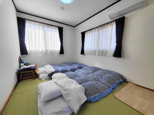 a bedroom with a large bed in a room with windows at Tetsu no YA Guesthouse for Railfans in Fuefuki