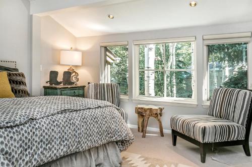 a bedroom with a bed and two chairs and windows at Villa's of Aspen by Snowmass Vacations in Aspen