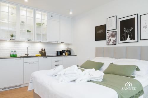 a white bedroom with white cabinets and a white couch at Apartament Baltic Amber z dostępem do basenów,strefy saun, jacuzzi przez cały rok- Pinea Apartments Pobierowo-SANNEL Apartments for rent in Pobierowo
