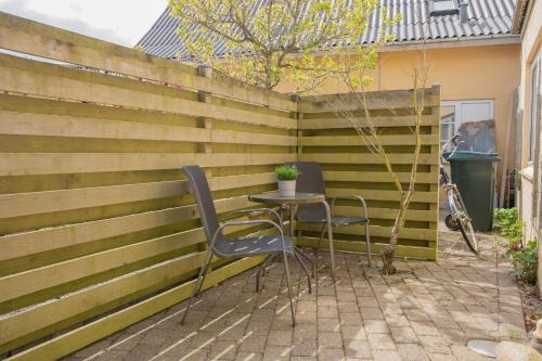 a patio with two chairs and a table in front of a fence at Grindsted - Billund Apartment 1 in Grindsted