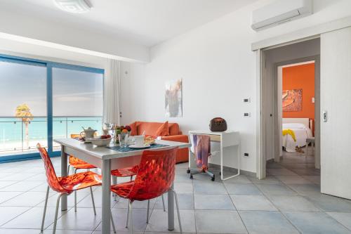 a living room with a table and red chairs at Terraces d'Orlando - Family Apartments with Sea View and Pool in Capo dʼOrlando