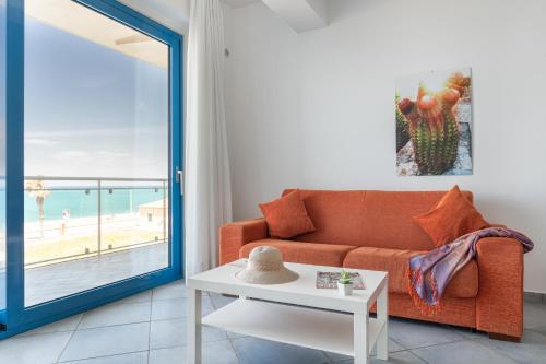 a living room with a couch and a view of the beach at Terraces d'Orlando - Family Apartments with Sea View and Pool in Capo dʼOrlando