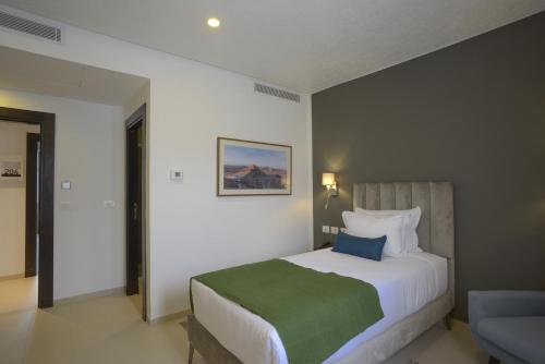a bedroom with a large bed with a green blanket at MAIA HOTEL SUITES in Tunis