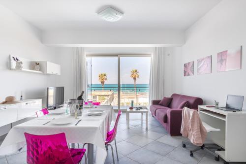 a living room with a table and purple chairs at Terraces d'Orlando - Family Apartments with Sea View and Pool in Capo dʼOrlando