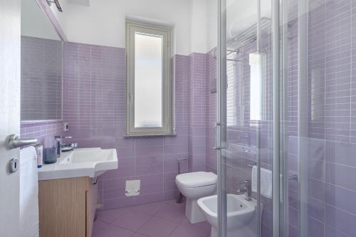 a purple bathroom with a toilet and a sink at Terraces d'Orlando - Family Apartments with Sea View and Pool in Capo dʼOrlando