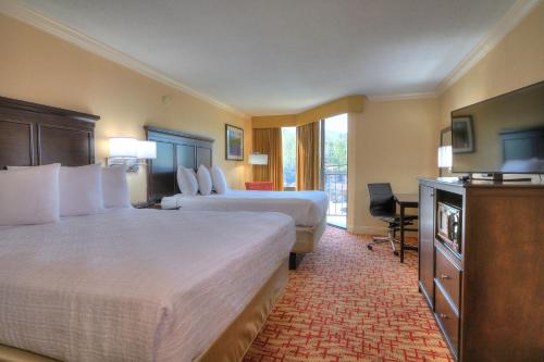 a hotel room with two beds and a flat screen tv at Edgewater Hotel and Conference Center in Gatlinburg