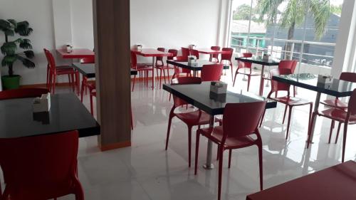 een eetkamer met tafels en rode stoelen bij HOTEL PINHEIRO CENTER in Pinheiro