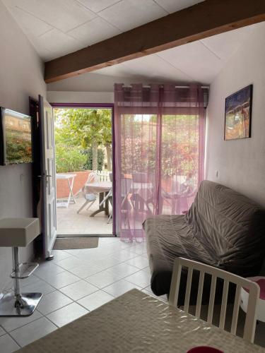 Una sala de estar con un sofá y una puerta corrediza de vidrio. en Maison dans résidence 3*proche plage, en Saint-Cyprien