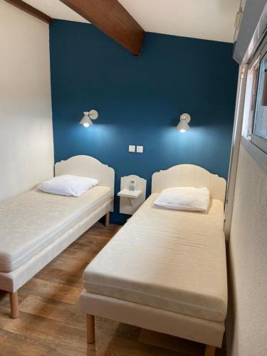 - 2 lits dans une chambre avec un mur bleu dans l'établissement Maison dans résidence 3*proche plage, à Saint-Cyprien