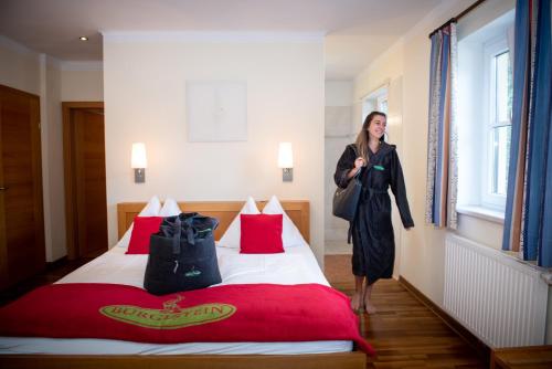 Eine Frau steht neben einem Bett in einem Zimmer in der Unterkunft Hotel Bürglstein in St. Wolfgang