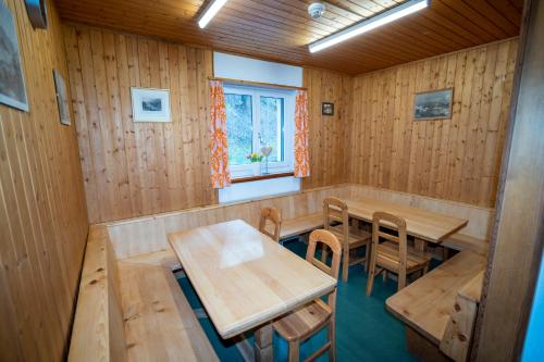 ein Zimmer mit Holztischen und -stühlen und einem Fenster in der Unterkunft Pensiun Lischana in Sent