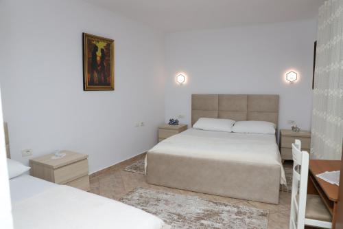 a white bedroom with a bed and a desk and a desk at Downtown Apartment 2 in Berat