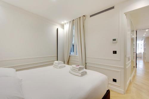 a white bedroom with a bed with towels on it at Stunning apartment with view at the very heart of Paris in Paris