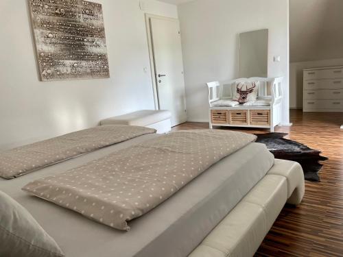 a bedroom with two beds and a chair and a dresser at Ferienwohnung H&H Happy Holiday in Velden am Wörthersee
