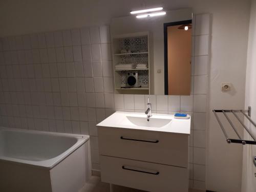 ein weißes Badezimmer mit einem Waschbecken und einer Badewanne in der Unterkunft Le Midi 2 in Trèbes