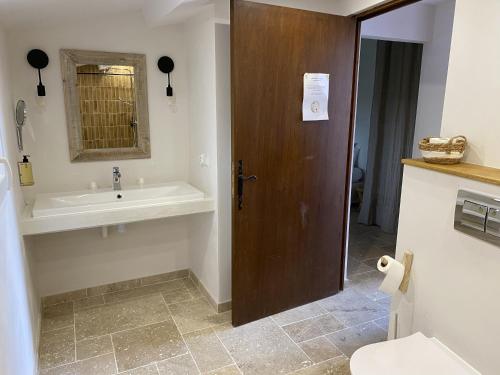 a bathroom with a sink and a wooden door at Hôtel du Pont Blanc in Saintes-Maries-de-la-Mer