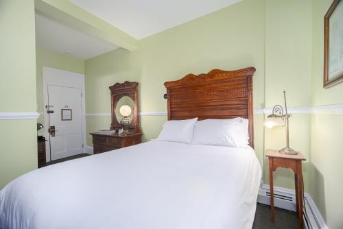 a bedroom with a bed with a wooden headboard and a mirror at Bedford Inn in Cape May