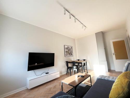 uma sala de estar com uma televisão de ecrã plano numa parede branca em Apartament RZ em Gdynia