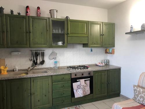 cocina con armarios verdes y fogones horno superior en Aria Dorata, en Torre dei Corsari