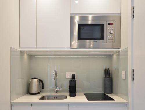 a kitchen with a sink and a microwave at StayPrime Marylebone Serviced Apartments in London