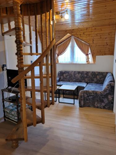 a living room with a staircase and a couch at Henrietta Apartmanház in Zalakaros