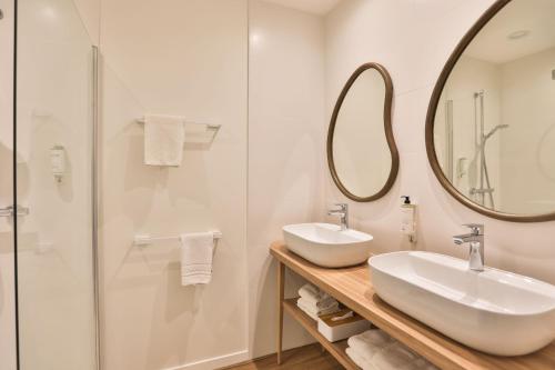 a bathroom with two sinks and a mirror at Hotel & Spa Les Roches Noires in Les Sables-dʼOlonne