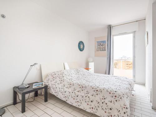 a white bedroom with a bed and a table at Apartment Soleil Bleu-8 by Interhome in Canet-en-Roussillon