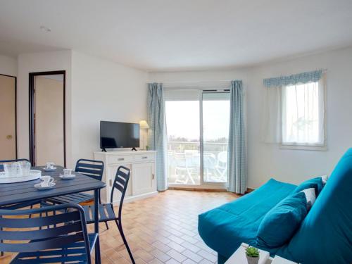 a living room with a blue couch and a table at Apartment Les Capitelles by Interhome in Saint-Cyprien-Plage