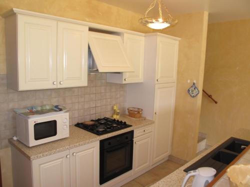 a kitchen with white cabinets and a microwave at Holiday Home La Cardeline by Interhome in Grillon