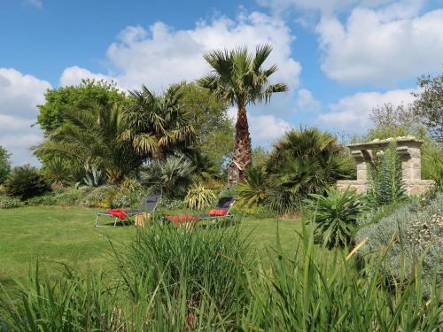 a park with palm trees and chairs in a field at Holiday Home Valhalla- chez Jules by Interhome in Planguenoual