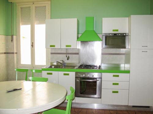 kuchnia z zielonymi i białymi szafkami oraz stołem w obiekcie Apartment Bellavista A by Interhome w mieście Cattolica